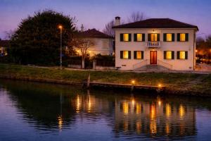 a house sitting next to a river at night at Villa Venezia Apartment in Dolo