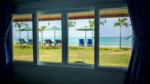 a window view of a beach with chairs and umbrellas at Lipa Bay Residence in Nathon Bay