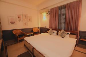 a bedroom with a large white bed and two chairs at Hotel Gargo Tower in Guwahati