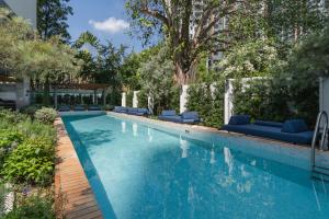 a swimming pool with blue lounge chairs and trees at The Akyra Bangkok 11 in Bangkok