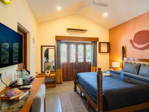 a bedroom with a bed and a table and a couch at The Hosteller Goa, Anjuna in Arpora