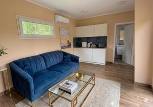 a living room with a blue couch and a kitchen at Domki La Bella 3 in Aleksandria