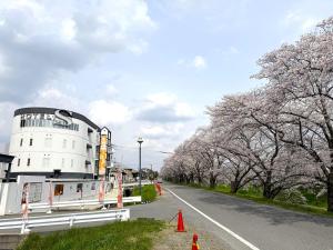 a building on the side of a road with cherry trees at Hotel S in Nara