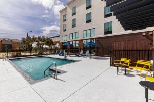 a swimming pool with yellow chairs and a building at Hampton Inn & Suites by Hilton Tomball Houston NW in Tomball