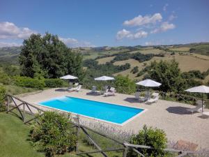 a swimming pool with chairs and umbrellas at Agriturismo Tre Querce in Penna San Giovanni