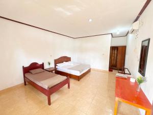 a bedroom with two beds and a table at Harus Damai Inn in Lagudri