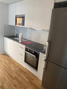 a kitchen with white cabinets and a black refrigerator at Nice flat in Barkarby in Järfälla