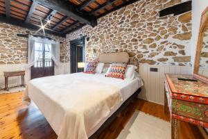 a bedroom with a bed and a stone wall at La Quintana de Los Valles in Benia de Onís