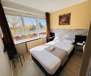 ein Schlafzimmer mit einem großen Bett und zwei Fenstern in der Unterkunft Hôtel OpalOriental Boulogne Sur Mer - gare ville et centre in Boulogne-sur-Mer
