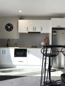 a kitchen with white cabinets and a table and a microwave at Swansea Cabins in Swansea