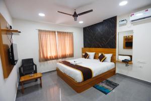 a bedroom with a bed and a chair and a television at Mantra Lodge in Shimoga