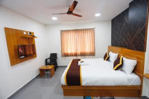 a hotel room with a bed and a ceiling fan at Mantra Lodge in Shimoga +5 photos