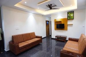 a living room with a couch and a tv at Mantra Lodge in Shimoga