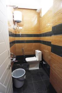 a bathroom with a toilet and a bucket at Mantra Lodge in Shimoga