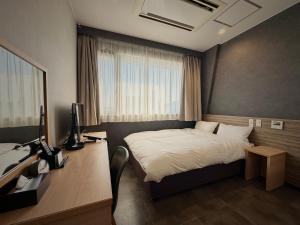 ein Schlafzimmer mit einem Bett und einem Schreibtisch mit Computer in der Unterkunft Hotel Sun Road in Amakusa