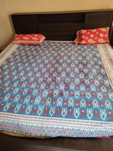 a bed with a blue comforter and two pillows on it at Cnc in Vadodara