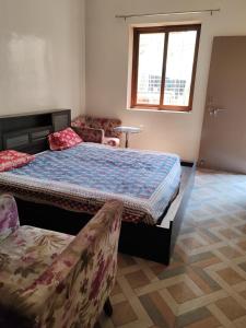 a bedroom with a bed and a couch and a window at Cnc in Vadodara