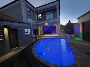 a large blue swimming pool in front of a house at XLA Home Guest house in eMalahleni