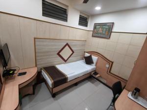 a small room with a bed and a desk at Anand Regency Majestic in Bangalore