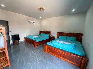 a bedroom with two beds with blue sheets and a television at HomeStay2 in Kaôh Rŭng