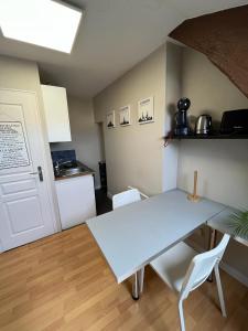 a kitchen with a blue table and white chairs at Studio rénové gare Dijon in Dijon
