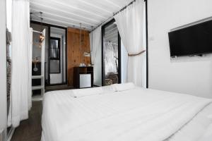 a bedroom with a white bed and a flat screen tv at serene hotel in Chiang Mai