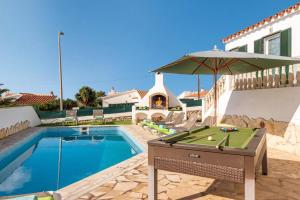a pool with a ping pong table and an umbrella at Villa Santi I by Villa Plus in Cala en Porter