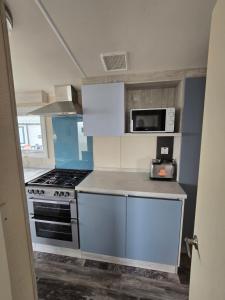 a kitchen with a stove and a microwave at Palm trees and the sea in Reighton