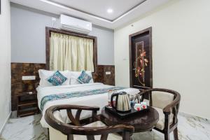 a bedroom with a bed and a table and a chair at Hotel Prestige Grand, Manikonda in Haidar Sāhibgūda