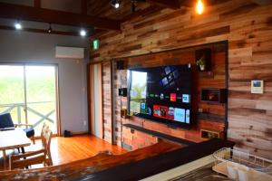 a living room with a wooden wall with a flat screen tv at 118 Terrace in Nakijin