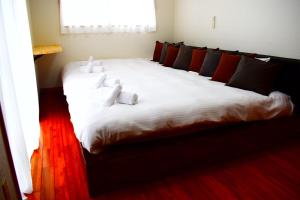 a large bed with white sheets and red pillows at 118 Terrace in Nakijin