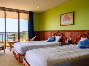 two beds in a room with green walls and a balcony at Garden BBQ and Stay ANCHOR in Miyakojima
