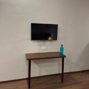 a table with a tv on a wall with a bottle on it at Stayverse noida in Greater Noida