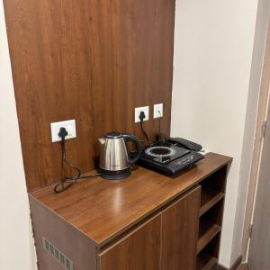 a tea kettle on top of a wooden cabinet at Stayverse noida in Greater Noida