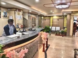 a man sitting at a counter in a lobby at Anand Regency Majestic in Bangalore