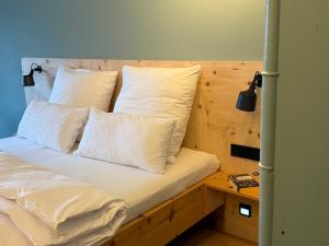 a bed with white pillows and a wooden headboard at "Unter Freunden", Design Meets Allgäu in Wertach