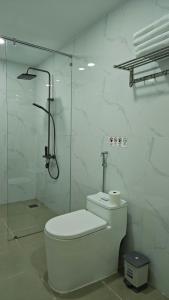 a white bathroom with a toilet and a shower at The Moon Hotel in Chánh Long