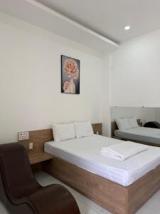 a bedroom with two beds and a chair in it at The Moon Hotel in Chánh Long