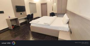 a room with a bed and a desk and a television at Hotel Peepal in Noida