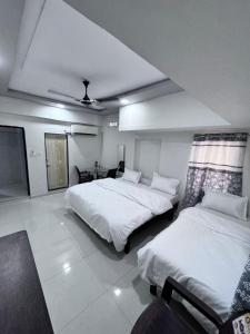 a bedroom with two beds and a table in it at Radha Krishna Guest House in Surat