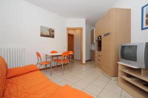 Residence Sole del Conero في أنكونا: غرفة معيشة مع أريكة وتلفزيون وطاولة