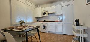 a kitchen with white cabinets and a table with chairs at LURRA Tierra Apartamento 1 in Sopuerta