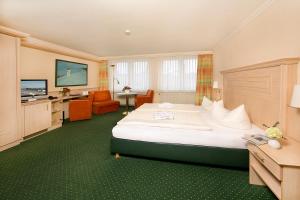 a hotel room with a large bed and a television at Hotel Dünenschloß in Zinnowitz