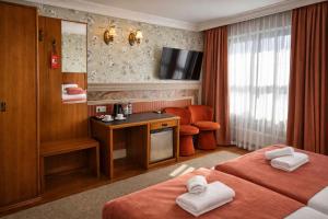 a hotel room with two beds and a desk at Heban Hotel in Toruń
