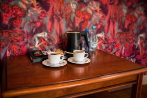 two cups of coffee sitting on a wooden table at Heban Hotel in Toruń