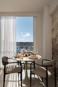 a dining room with a table and chairs and a large window at PortoVista Luxury Urban Suites by BiNoBi! in Thessaloniki
