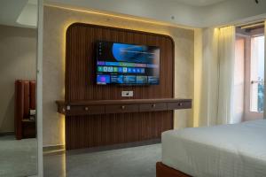 a room with a bed and a television on a wall at Millennium Hotel in Nashik