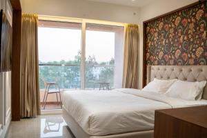 a bedroom with a large bed and a large window at Millennium Hotel in Nashik
