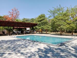 a swimming pool with a pavilion and trees at Olive Resort & Villas in Khawāsa