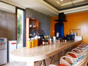 a bar in a restaurant with orange walls and chairs at Garden BBQ and Stay ANCHOR in Miyakojima
